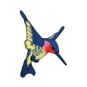 Peut inclure: Un patch brodé représentant un colibri bleu, jaune et rouge. Le colibri est en vol, les ailes déployées.