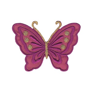 Könnte beinhalten: Ein rosa Schmetterling mit goldenen Akzenten. Der Schmetterling ist gestickt und hat ein detailliertes Design.