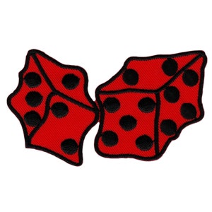 Op de afbeelding: Twee rode dobbelstenen met zwarte stippen, geborduurd op een stoffen patch.