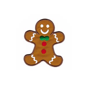 Könnte beinhalten: Ein Lebkuchenmann mit einem weißen Lächeln, einer grünen Schleife und roten Knöpfen. Der Lebkuchen ist braun und hat weißen Zuckerguss an den Rändern.