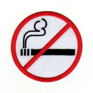 Op de afbeelding: Een rode cirkel met een diagonale rode lijn erdoorheen. Binnen de cirkel bevindt zich een zwart-witte afbeelding van een sigaret met rook die eruit komt. De tekst "No Smoking" is niet zichtbaar op de afbeelding.