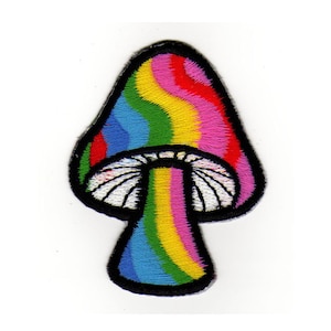 Könnte beinhalten: Gestickter Patch in Form eines Pilzes mit einem weißen Hut und einem Stiel mit Regenbogenmuster, in Regenbogenfarben.
