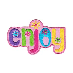 Könnte beinhalten: Ein rosa gestickter Aufnäher mit dem Wort "enjoy" in bunten Buchstaben und Blumen.