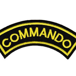 Könnte beinhalten: Schwarzer und gelber gestickter Aufnäher mit dem Wort "COMMANDO" in gelben Buchstaben.