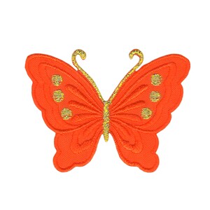 Op de afbeelding: Applicatie van een oranje stoffen vlinder met gouden geborduurde details. De vlinder heeft een gegolfde rand en een textuur.