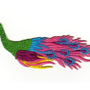 Op de afbeelding: Een kleurrijk geborduurd pauw-patch met een groen lichaam, blauwe en roze staartveren en gele accenten.