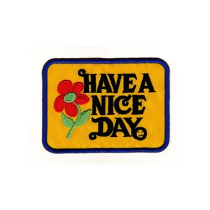 May include: Yellow embroidered patch with blue edging. The patch features a red flower with a green stem and the text "HAVE A NICE DAY" in black.