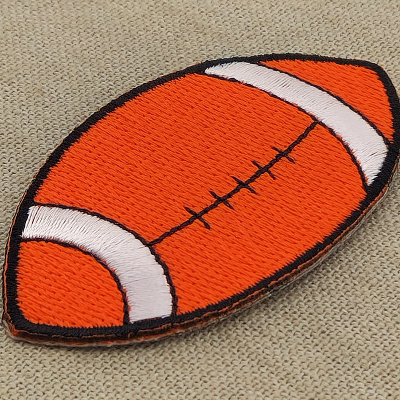 May include: Orange and white embroidered iron-on patch shaped like a football.