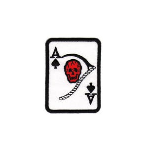 Könnte beinhalten: Ein gestickter Aufnäher mit einem As Pik Spielkartenmotiv mit Totenkopf und Knochen. Der Totenkopf ist rot und die Knochen sind schwarz.