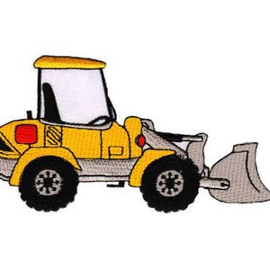 May include: A yellow toy construction vehicle with a gray bucket. The vehicle has a black cab with a white window and black wheels.