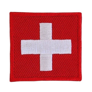 Könnte beinhalten: Ein roter gestickter Aufnäher mit einem weißen Kreuz in der Mitte. Der Aufnäher hat einen weißen Rand.