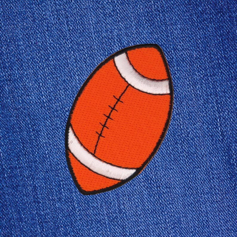 May include: Orange and white embroidered patch of an American football on a blue denim background.
