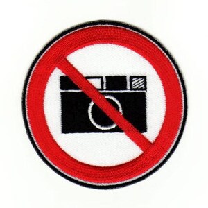 Op de afbeelding: Een rode cirkel met een diagonale lijn door een zwart-wit camera-icoon. De tekst "No Photography" is niet zichtbaar op de afbeelding.