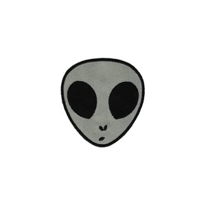 May include: A grey alien face with black eyes and a small mouth.