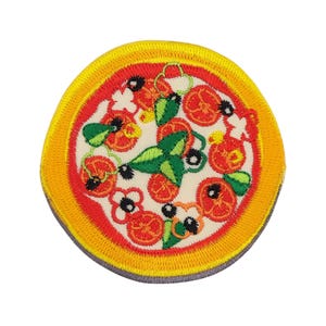 Könnte beinhalten: Gestickter Bügelaufkleber mit einer Pizza mit roten, orangen, grünen und schwarzen Belägen. Die Pizza ist von einem gelben und orangen Rand umgeben.