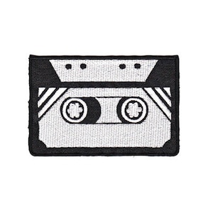 Könnte beinhalten: Schwarz-weiß gestickter Aufnäher einer Kassette. Das Band ist weiß mit schwarzen Streifen und zwei schwarzen Kreisen. Der Aufnäher ist von einem schwarzen Rand umgeben.