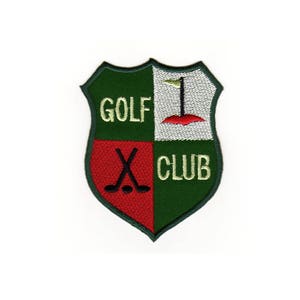 Puede incluir: Parche bordado verde y rojo con forma de escudo. El parche tiene las palabras "GOLF CLUB" y un diseño de palo de golf y bandera.