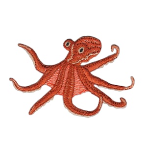 Könnte beinhalten: Ein orangefarbener gestickter Oktopus mit acht Tentakeln. Der Oktopus ist ein beliebtes Meerestier und wird oft in nautischen Bastelarbeiten verwendet.