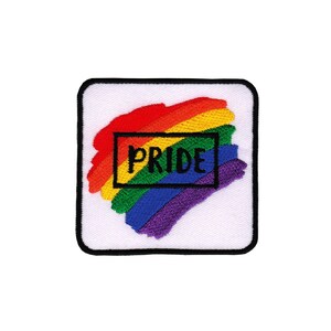 Könnte beinhalten: Ein weißer quadratischer Patch mit einem regenbogenfarbenen Design und dem Wort "PRIDE" in einem schwarzen Kasten.