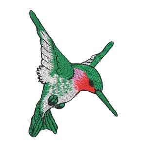 Könnte beinhalten: Gestickter Aufnäher mit einem Kolibri im Flug. Der Vogel ist in Grün, Weiß, Rot und Rosa gehalten. Der Aufnäher ist zum Aufnähen oder Aufbügeln auf Stoff gedacht.
