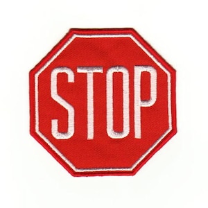 Puede incluir: Señal de stop octogonal roja con borde blanco y texto blanco que dice "STOP".