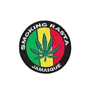Könnte beinhalten: Ein runder schwarzer Patch mit weißem Text, der "Smoking Rasta Jamaique" lautet, und einem grünen Marihuana-Blatt auf rotem, gelbem und grünem Hintergrund.