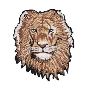 Könnte beinhalten: Gestickter Löwenkopf-Patch mit brauner und weißer Mähne. Der Löwe hat einen ernsten Ausdruck mit geschlossenem Maul und einem weißen Bart.