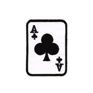 Könnte beinhalten: Eine weiße Spielkarte mit einem schwarzen gestickten As der Kreuz. Die Karte ist von einem schwarzen Rand umgeben.