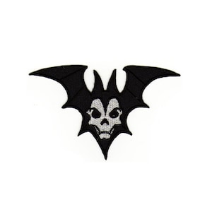 Könnte beinhalten: Schwarzer gestickter Bügeleisen-Aufnäher mit einer Fledermaus mit einem Schädel in der Mitte. Der Schädel ist weiß mit schwarzen Details.
