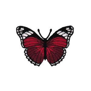 Puede incluir: Parche de mariposa bordado en rojo con detalles en blanco y negro.