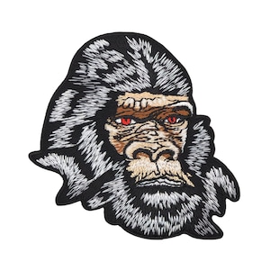 May include: Embroidered patch of a gorilla's face with a black and white fur design and red eyes.