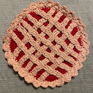 Peut inclure: Un dessous de verre fait à la main en crochet en forme de tarte. Le dessous de verre présente un motif de croûte en treillis de couleur beige clair, avec une garniture rouge. Le bord du dessous de verre a une bordure festonnée. Décoration de cuisine.