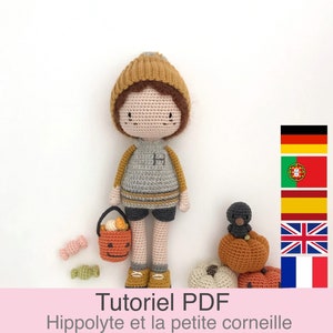 Może przedstawiać: Lalka amigurumi wykonana na szydełku w brązowym kapeluszu, szarym swetrze i niebieskich spodenkach. Lalka trzyma wiaderko w kształcie dyni z cukierkami. Lalka stoi obok małego czarnego ptaka siedzącego na dyni. Obraz zawiera tekst "Tutoriel PDF Hippolyte et la petite corneille".