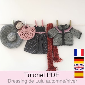 Op de afbeelding: Een gehaakte poppenoutfitset met een grijze hoed, een roze-witte jurk, een grijze trui en een rode sjaal. De set hangt aan een waslijn met wasknijpers. De tekst "Tutoriel PDF Dressing de Lulu automne/hiver" staat onderaan de afbeelding. De vlaggen van Frankrijk, Duitsland, het Verenigd Koninkrijk en Spanje staan in de rechterbenedenhoek.