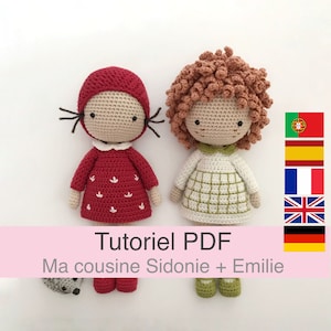 May include: Crochet pattern PDF for two amigurumi dolls, one with a red dress and red hat, the other with a green and white dress. The dolls are named Sidonie and Emilie. The pattern is available in multiple languages.