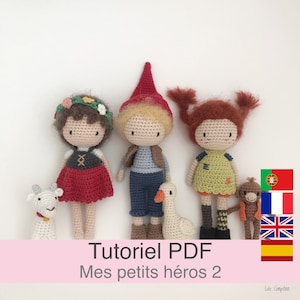 Peut inclure: Un tutoriel PDF au crochet pour réaliser trois poupées amigurumi, une fille avec une robe rouge et une couronne de fleurs, un garçon avec une chemise bleue et un pantalon marron, et une fille avec une robe verte et des cheveux bruns. Les poupées tiennent un chèvre blanc, une oie blanche et un singe brun. Le patron est intitulé "Mes petits héros 2" et est disponible en plusieurs langues.