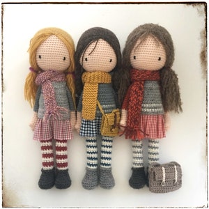 Peut inclure: Trois poup&eacute;es en crochet portant des &eacute;charpes et des jupes color&eacute;es. Chaque poup&eacute;e porte une &eacute;charpe et une jupe de couleur diff&eacute;rente. Les poup&eacute;es sont debout sur une surface blanche.