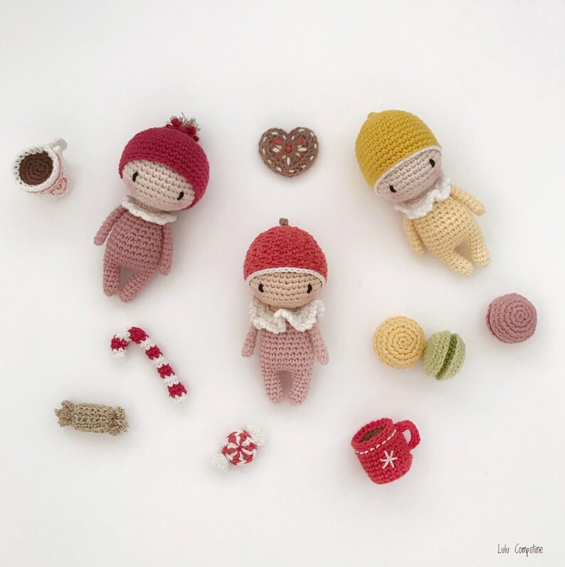 May include: A collection of handmade crocheted dolls, candy canes, and other holiday-themed decorations. The dolls are dressed in red, yellow, and pink outfits.