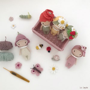 Puede incluir: Una colecci&oacute;n de mu&ntilde;ecas de ganchillo hechas a mano y criaturas en miniatura, incluyendo una oruga, una abeja, una mariquita y un caracol. Las mu&ntilde;ecas visten sombreros y trajes con tem&aacute;tica floral, con hilo y un ganchillo.