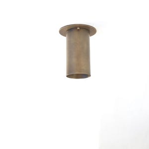 May include: A cylindrical, bronze-colored light fixture with a circular base and a matching top. The fixture is suspended from the ceiling, showcasing a minimalist design. The fixture is made of metal.