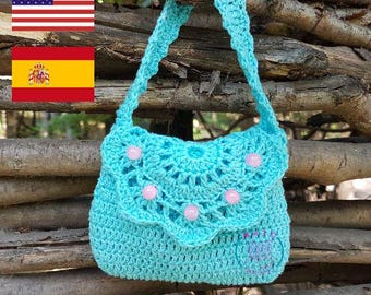 May include: A bright turquoise crocheted handbag featuring a scalloped flap adorned with five round, light pink beads. The bag has a single crocheted strap and a small, circular pink logo printed on the lower right corner of the main body.
