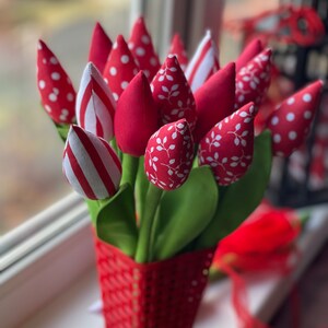 Puede incluir: Un ramo de tulipanes de tela roja con lunares blancos, rayas y patrones de hojas en una cesta tejida roja.