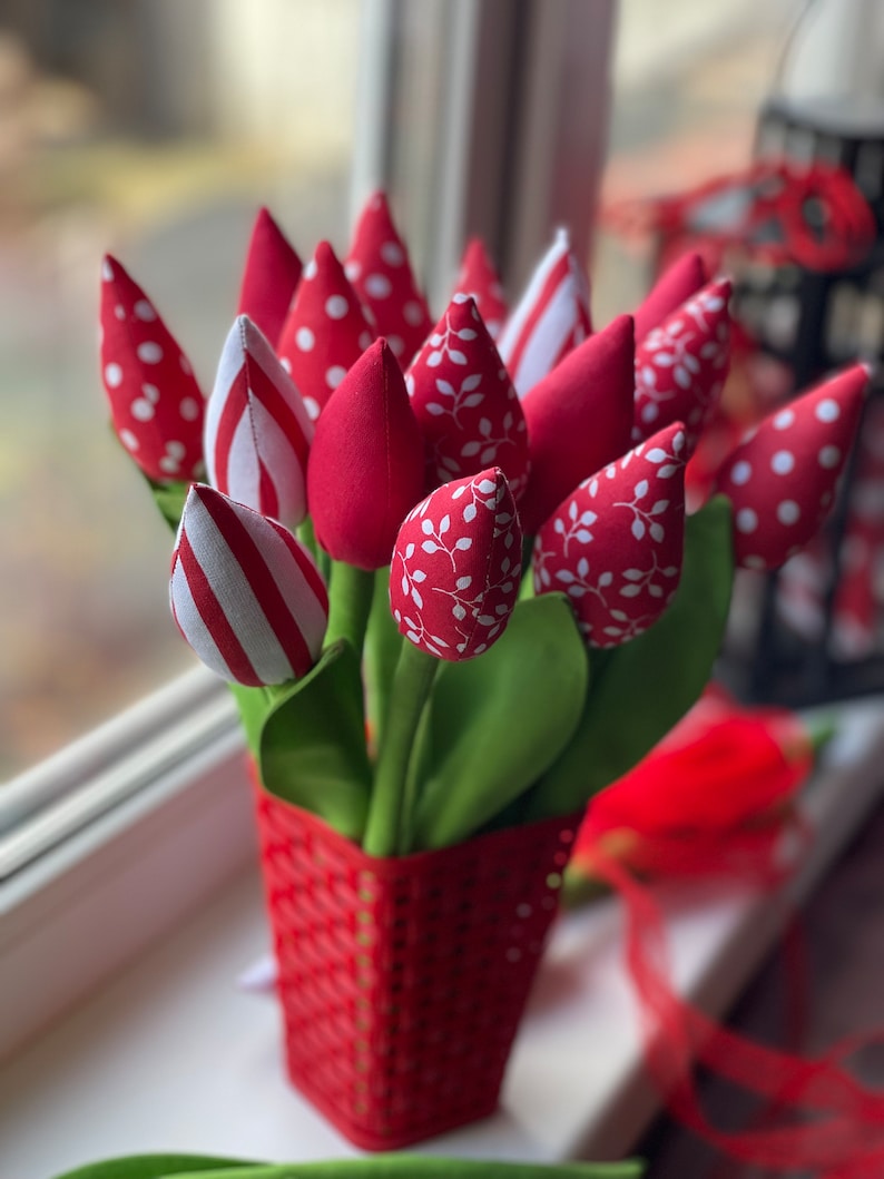 Puede incluir: Un ramo de tulipanes de tela roja con lunares blancos, rayas y patrones de hojas en una cesta tejida roja.
