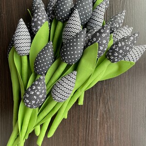 May include: A bouquet of black and white fabric tulips with green stems. The tulips have different patterns, including polka dots, zigzags, and floral designs.