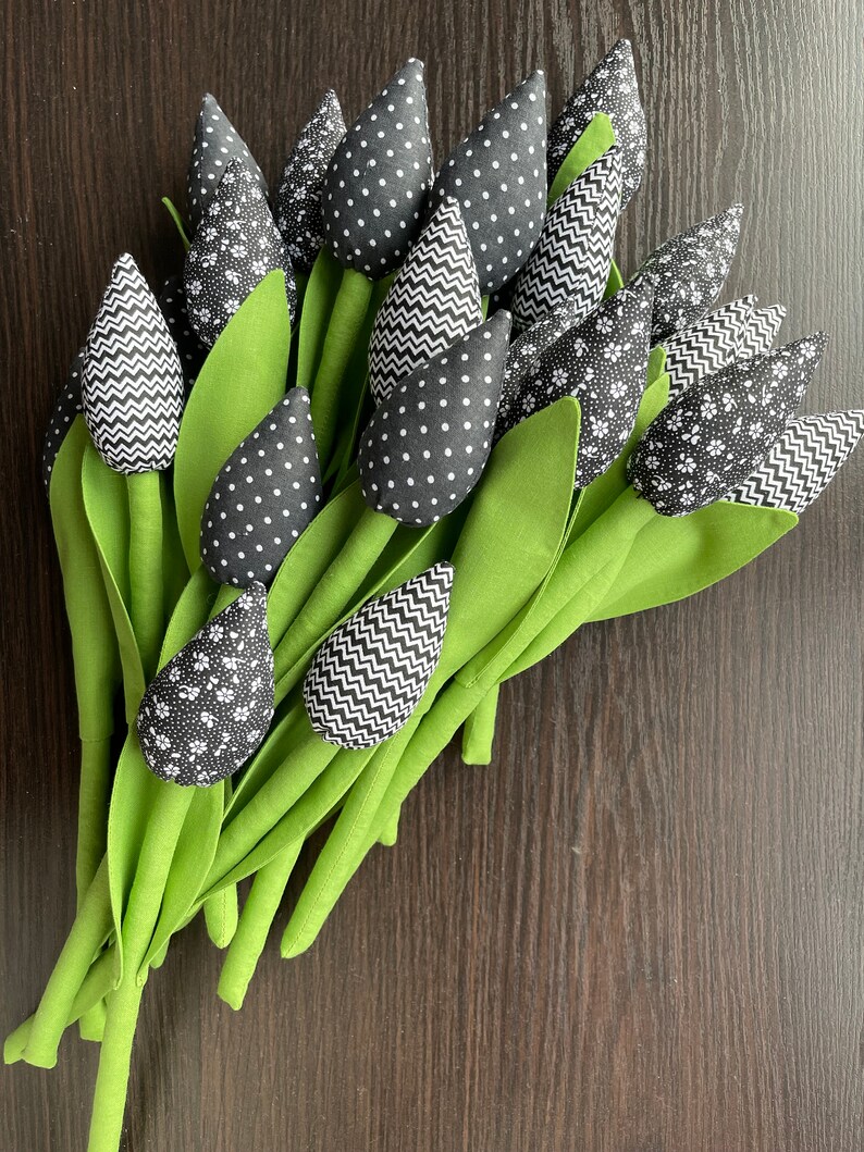 May include: A bouquet of black and white fabric tulips with green stems. The tulips have different patterns, including polka dots, zigzags, and floral designs.