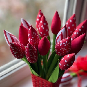 Puede incluir: Un ramo de tulipanes de tela roja con lunares blancos y patrones de hojas en una cesta de mimbre roja.