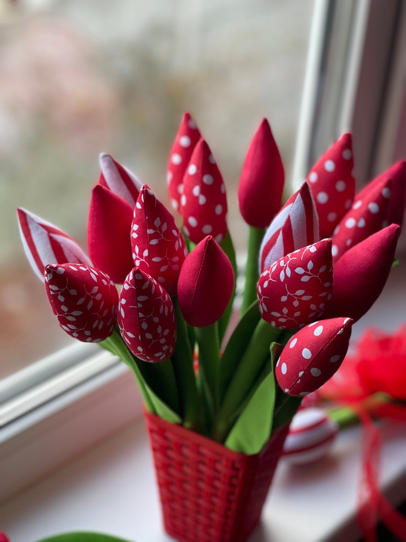 Puede incluir: Un ramo de tulipanes de tela roja con lunares blancos y patrones de hojas en una cesta de mimbre roja.