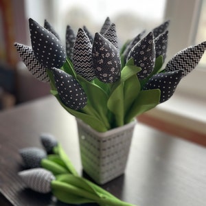 May include: A bouquet of black and white fabric tulips in a black and white striped vase. The tulips have different patterns, including polka dots, zigzags, and floral prints.