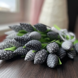May include: A bouquet of black and white fabric tulips with different patterns. The tulips are arranged in a cluster and have green stems.