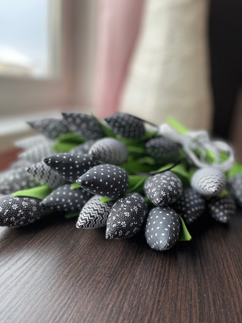 May include: A bouquet of black and white fabric tulips with different patterns. The tulips are arranged in a cluster and have green stems.